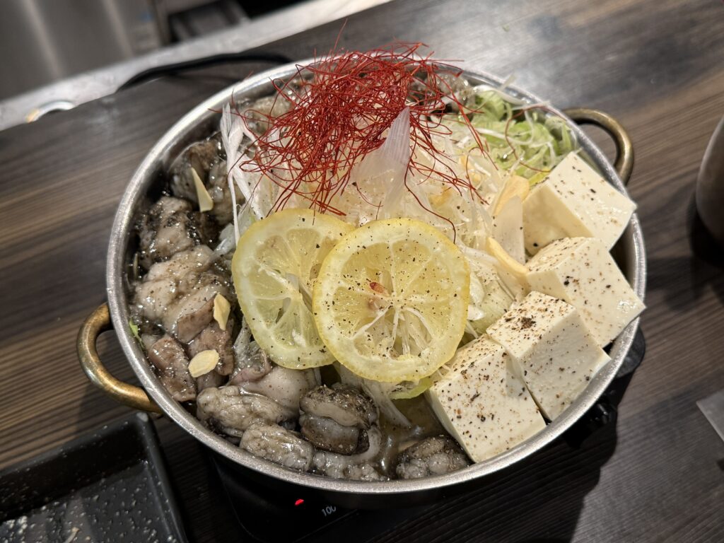 もつ鍋仙頭博多住吉店で提供される塩もつ鍋の鍋姿、透き通った塩スープにキャベツとねぎ、にんにくが浮かび、香ばしく炙ったもつがたっぷり並ぶ博多もつ鍋食べ比べ1軒目の一品