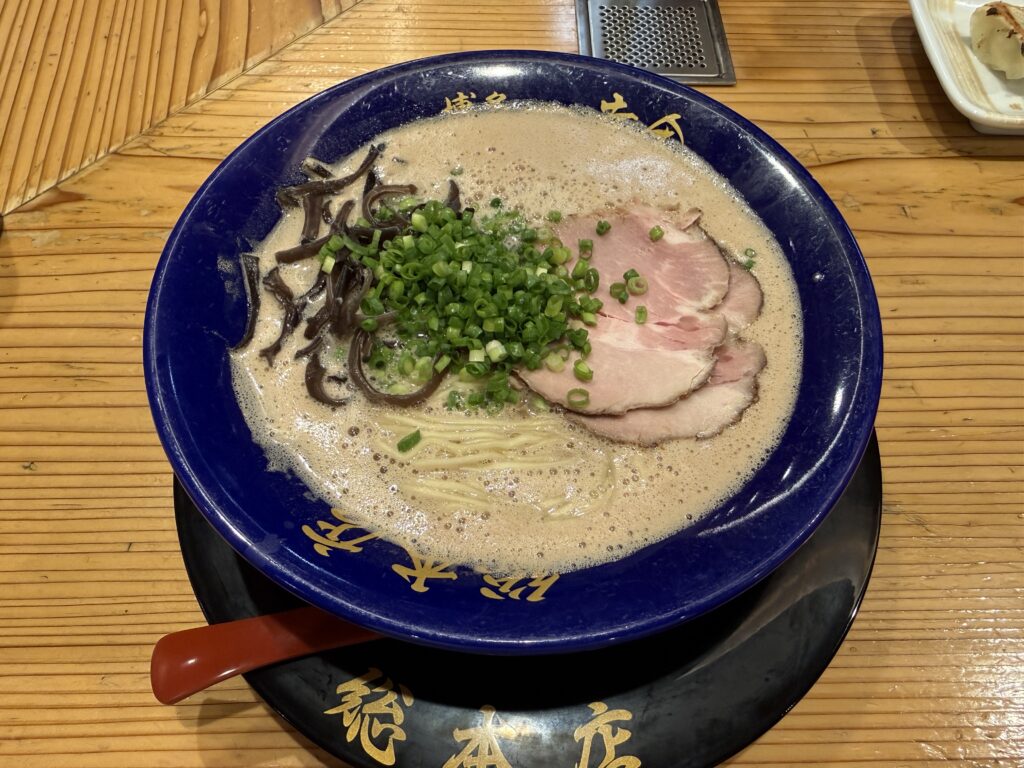 博多一幸舎 総本店で提供される元祖泡系豚骨ラーメンの一杯で、表面がカプチーノのようにふわっと泡立った濃厚スープに博多細麺が映える、もつ鍋後のシメにも軽やかに食べられる金曜深夜の名店の看板メニュー