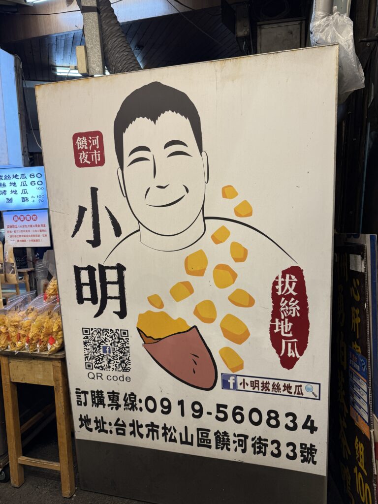 饒河街観光夜市で見つけた大学芋の屋台の様子で、蜜をたっぷりかけた甘い揚げ芋が並び、台北の夜市グルメとして日本の大学芋によく似た見た目ながら現地ならではの香ばしさが伝わる一枚