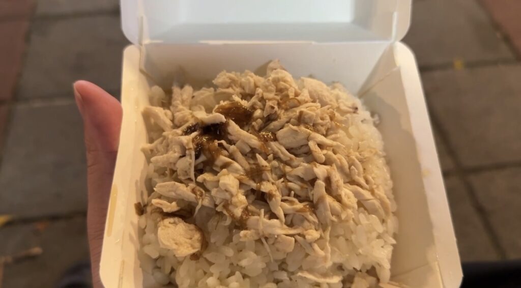 寧夏夜市の屋台で購入した台湾名物・鶏肉飯(ジーローハン)を白い容器に盛り付けた状態。細かく裂いた鶏肉と煮汁がご飯にかかった一杯で、台北の夜市グルメ実食レビューを伝える一品