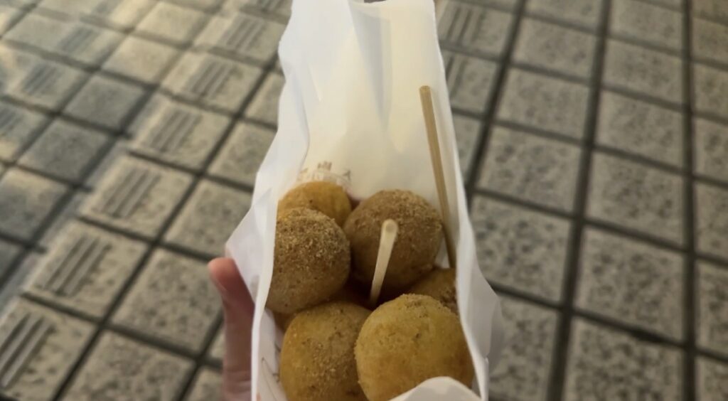 寧夏夜市で営業するさつまいもボール屋台の店頭スナップで、揚げ油の鍋や丸く成形された生地が並ぶ調理風景を捉えたカット。台北夜市食べ歩き比較記事で甘さ控えめながら油使用量の多さを伝える参考画像