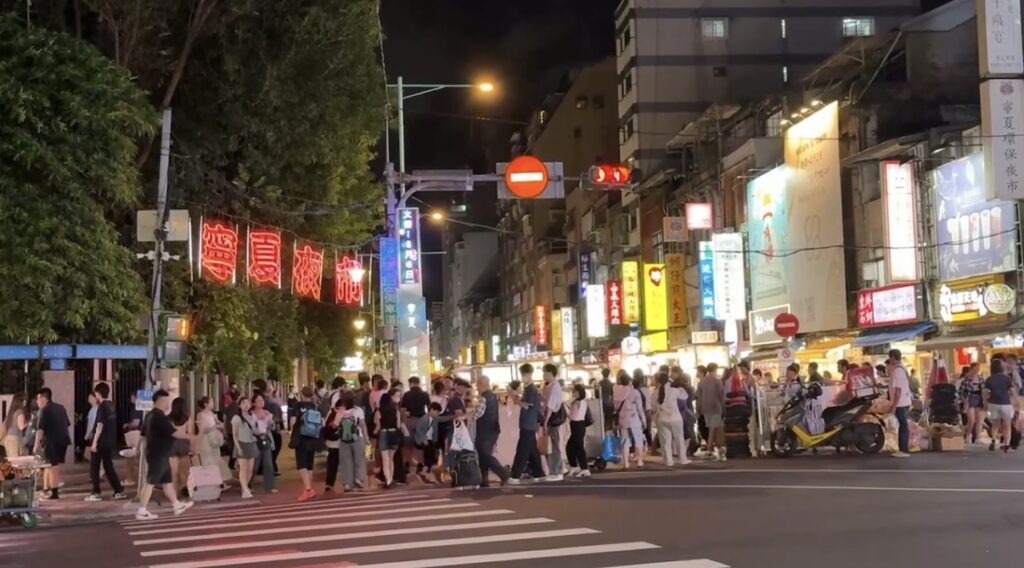 夜の寧夏夜市の通りを写したスナップで、台北旅行1日目に訪れた屋台街の雰囲気を紹介。大きすぎない規模で気軽に食べ歩きでき、夜市初心者でも歩きやすい人通りや明かりの様子が伝わる一枚