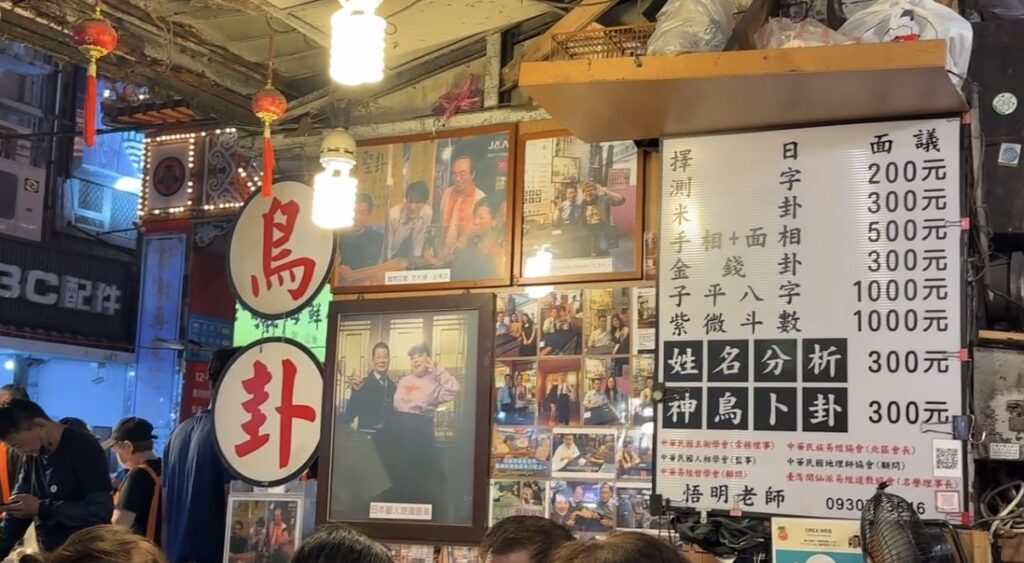 饒河街観光夜市の路地に佇む鳥占いの屋台の様子。志村けんさんや渡辺直美さんも訪れたと紹介される台湾ならではの占い店で、食べ歩き以外に印象に残る台北夜市の文化体験スポット